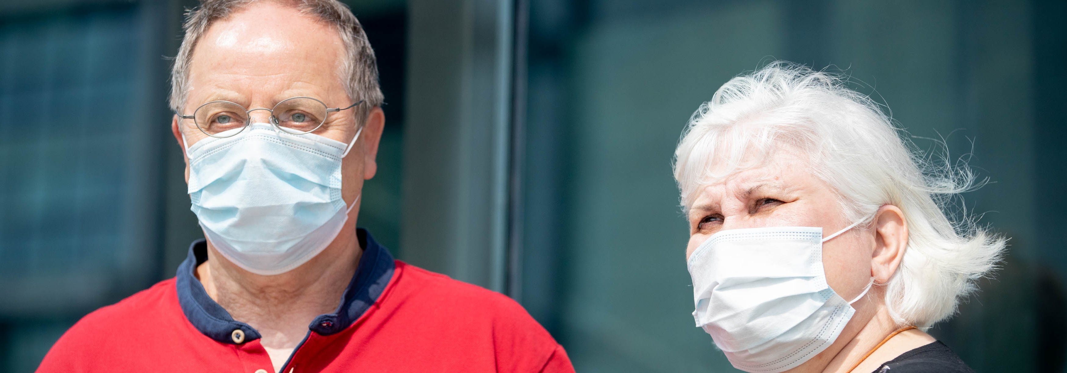 Das Foto zeigt einen Mann und eine Frau. Beide tragen eine Atemmaske. Das Foto deutet auf eine Pandemie-Situation hin.