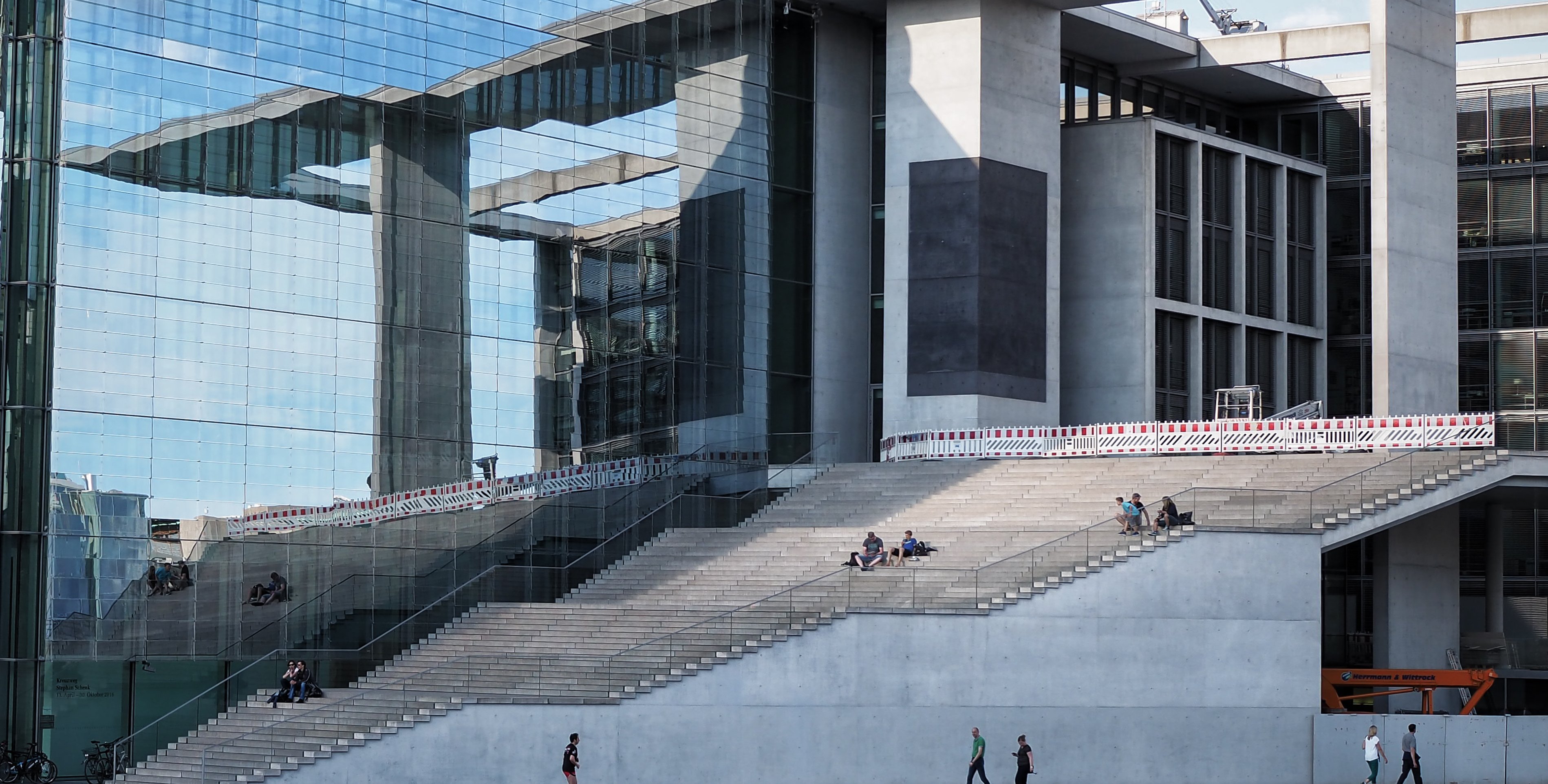 Das Foto zeigt einen Teil eines Geb&auml;udes im Regierungsviertel. Zu sehen ist eine gl&auml;serne Fassade und eine hohe Treppe.